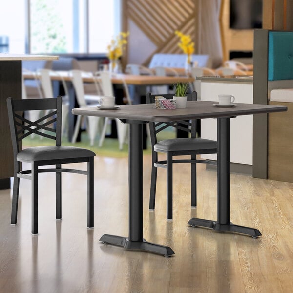 A close-up of a Lancaster Table & Seating white birch and ash table top on a table with chairs.