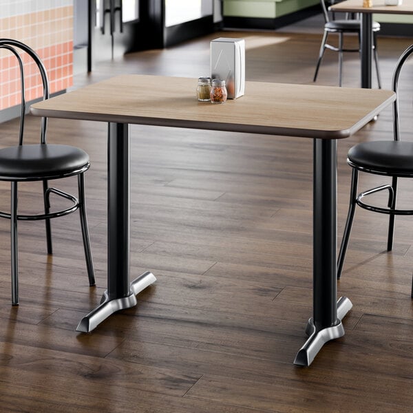 A rectangular standard height table with a reversible white birch and ash laminated top and a black cast iron base.