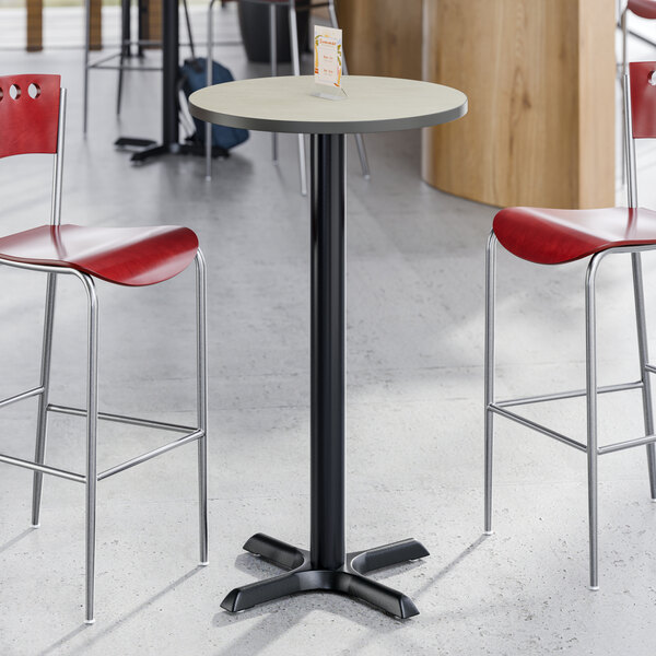 A round, bar-height table with a reversible gray and white laminated top and a black cast iron base.