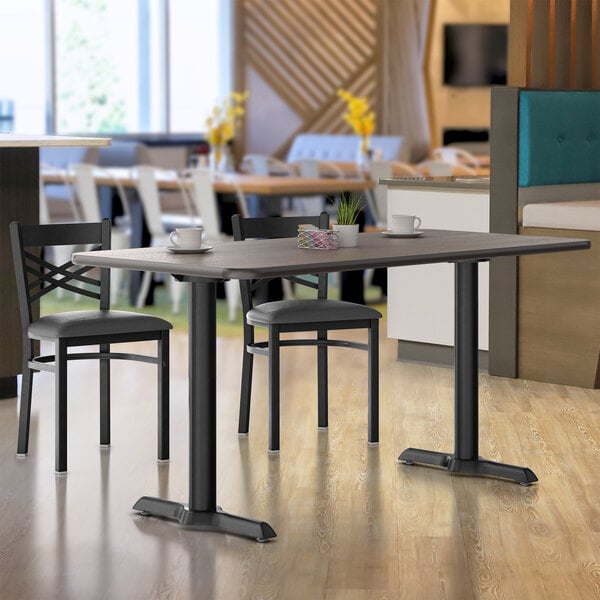 A Lancaster Table & Seating white birch and ash laminated table and base with a chair and cup on it.