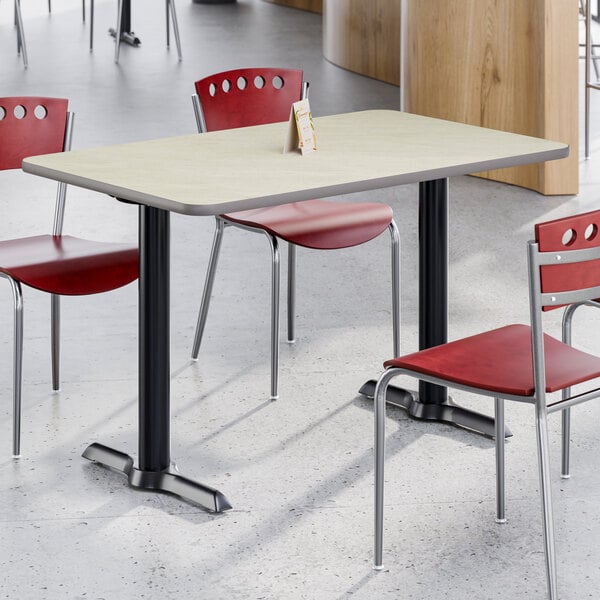 A rectangular standard height table with a reversible gray and white laminated top and a black cast iron base, surrounded by red chairs.