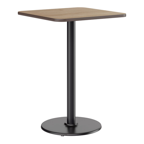 A square bar height table with a reversible white birch and ash laminated top and a black cast iron base.
