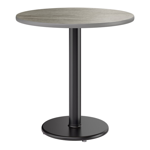 A round standard height table with a reversible gray and white laminated top and a black cast iron pedestal base.