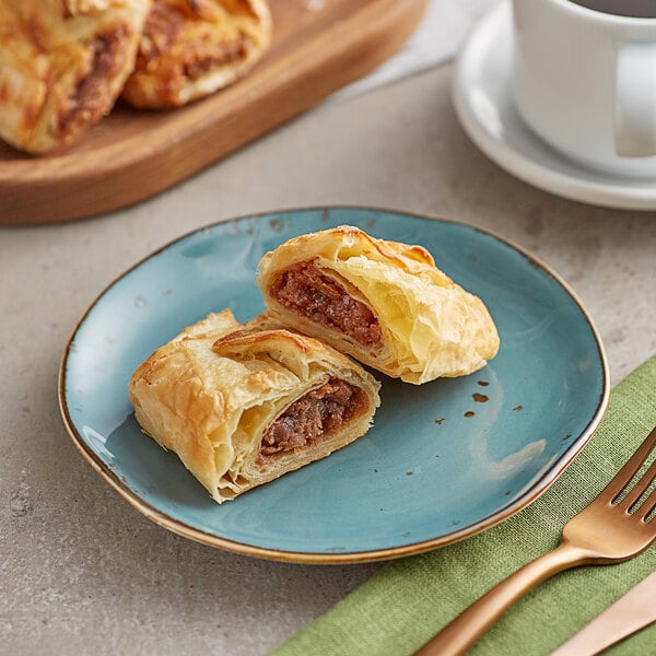 A plate with Orange Bakery almond filled croissants and a cup of coffee on a table.