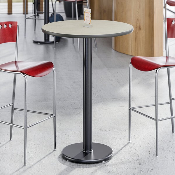A round bar height table with a reversible gray and white laminated top and a black cast iron base.