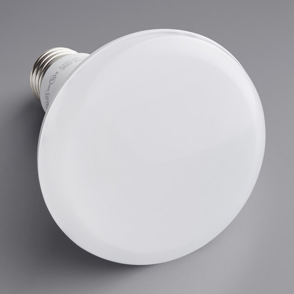 A TCP BR30 LED light bulb with white light on a gray surface.