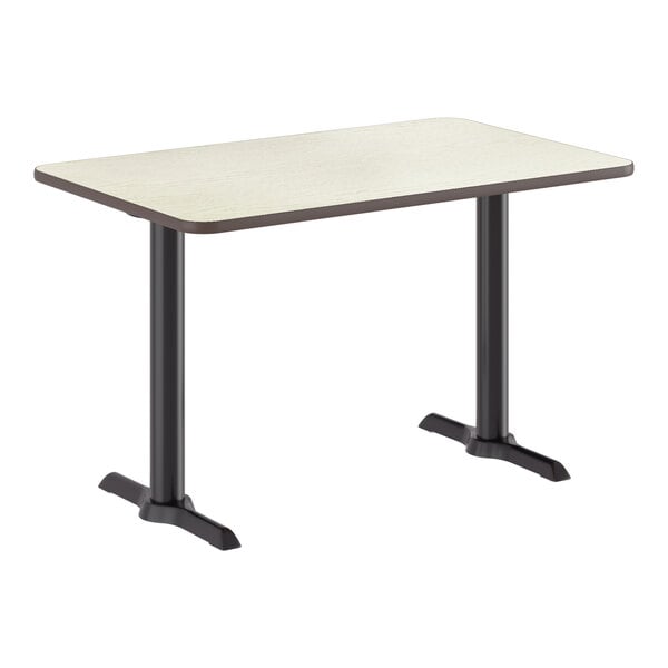 A rectangular standard height table with a reversible white birch and ash laminated top and a black cast iron base.
