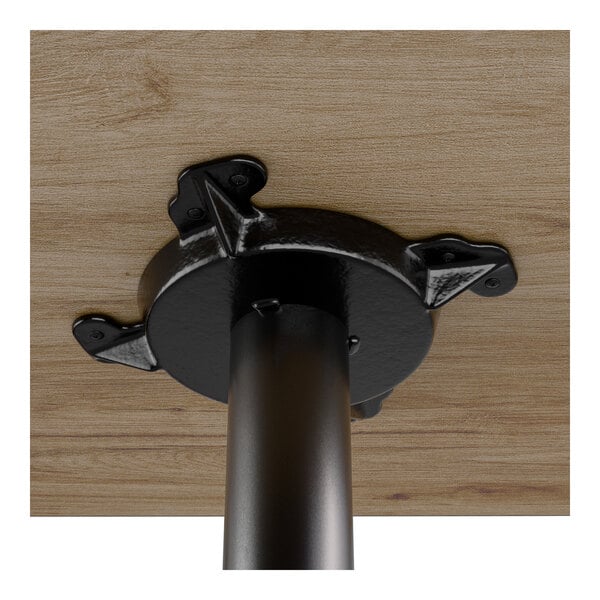 A close-up view of the underside of a wooden table top attached to a black metal table base.