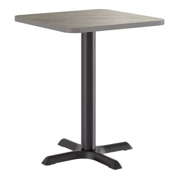 A square standard height table with a reversible gray and white laminated top and a black cast iron base.