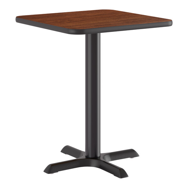 A square standard height table with a reversible walnut or oak laminated top and a black cast iron base.