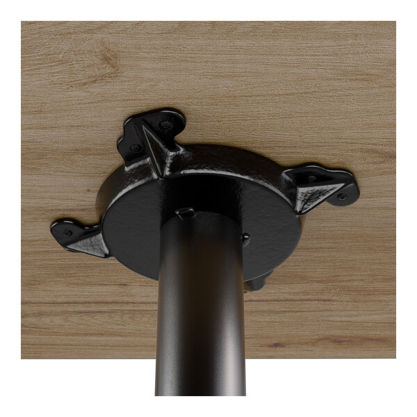 A close-up view of the underside of a bar height table showing a black cast iron base attached to a wood-finished tabletop.