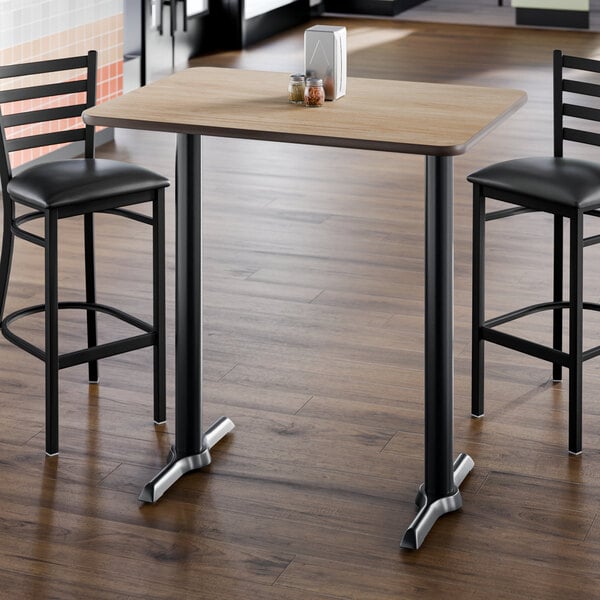 A rectangular bar height table with a reversible white birch and ash laminated top and a black cast iron base.