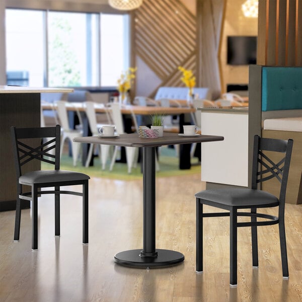 A Lancaster Table & Seating white birch and ash laminated table top on a table with two chairs.