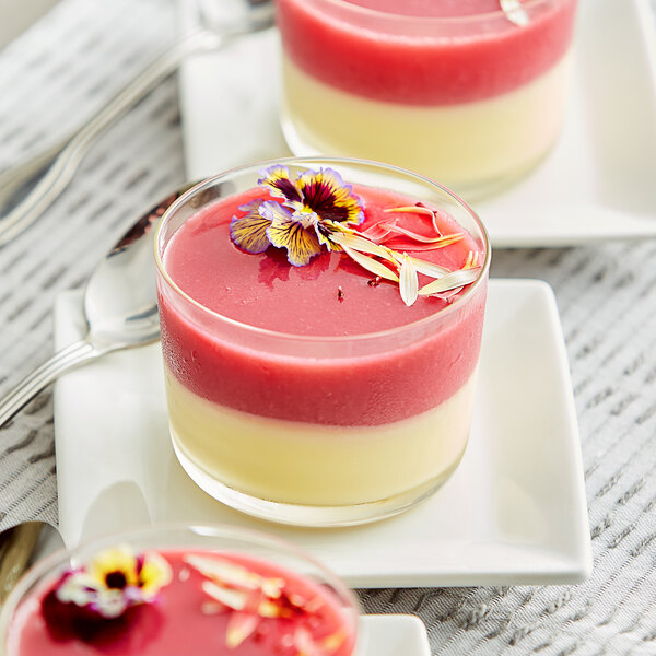 A close-up of a dessert in a glass with red and white layers.