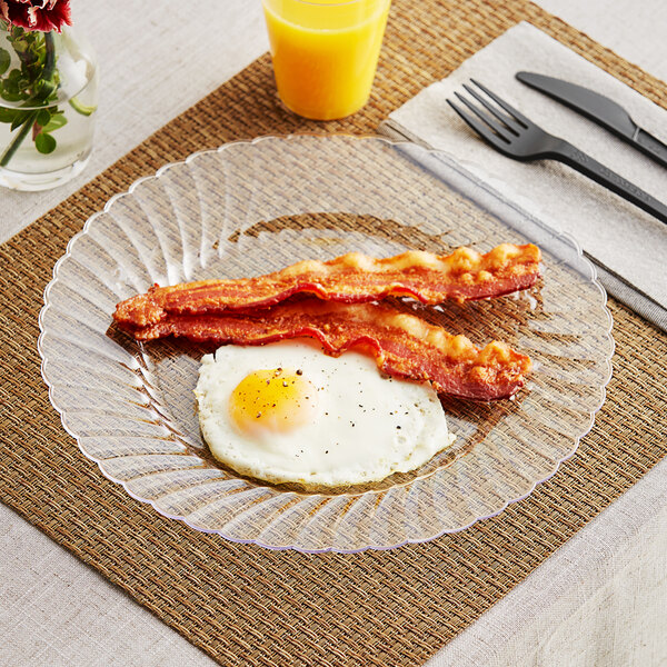 A WNA Comet clear plastic plate with bacon and eggs on it.