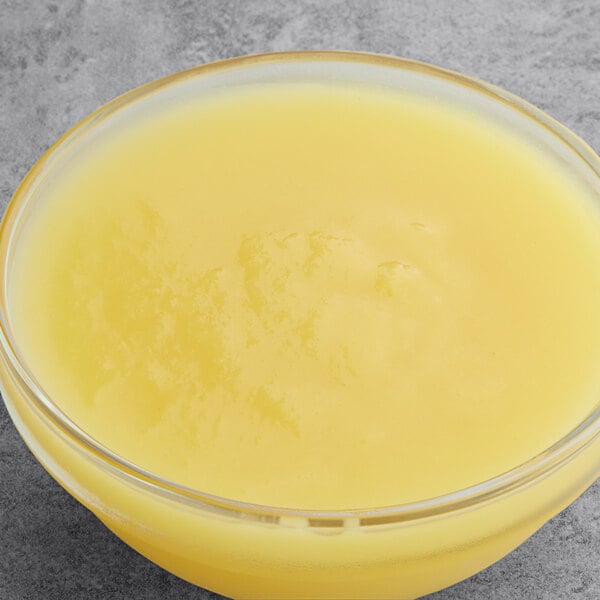 A bowl of Les Vergers Boiron ginger puree on a gray surface.