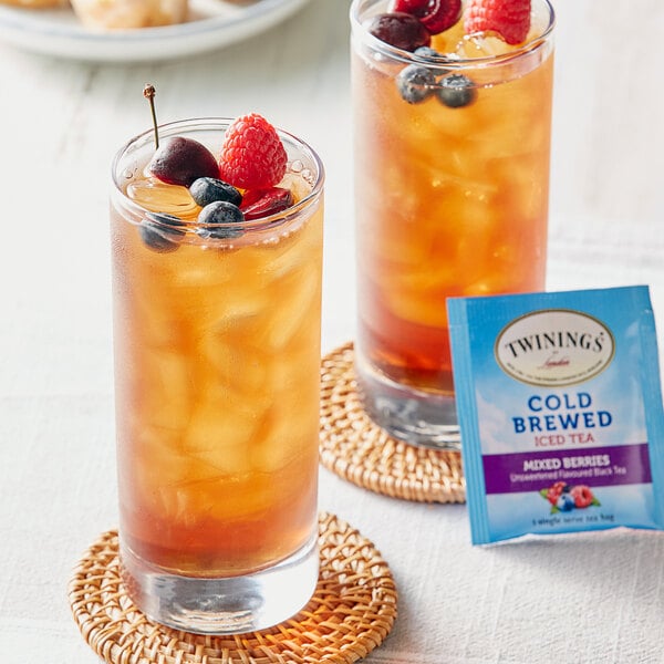 Two glasses of Twinings iced tea with berries and a packet of tea.