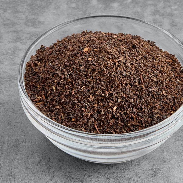 A bowl of Twinings English Breakfast loose leaf tea on a gray surface.