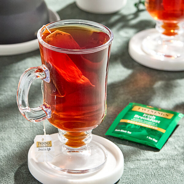 A glass cup of Twinings Irish Breakfast decaffeinated tea with a tea bag in it.