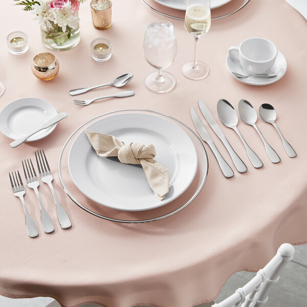 A table set with plates and Acopa Triumph stainless steel spoons, forks, and knives.