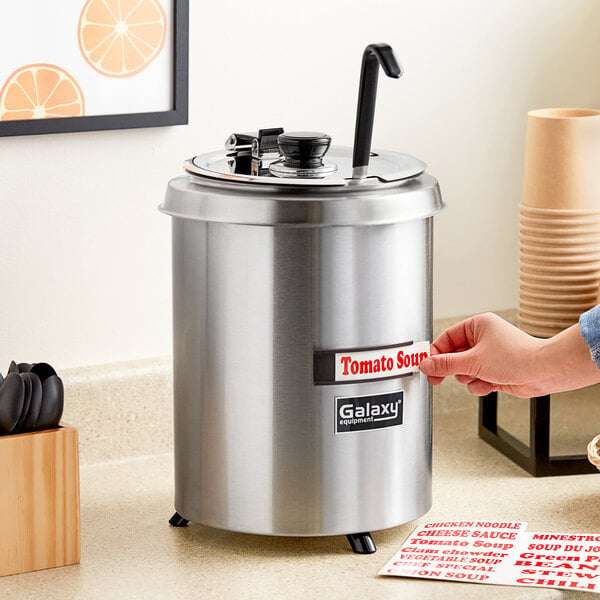 A person using a Galaxy round brushed steel soup warmer.