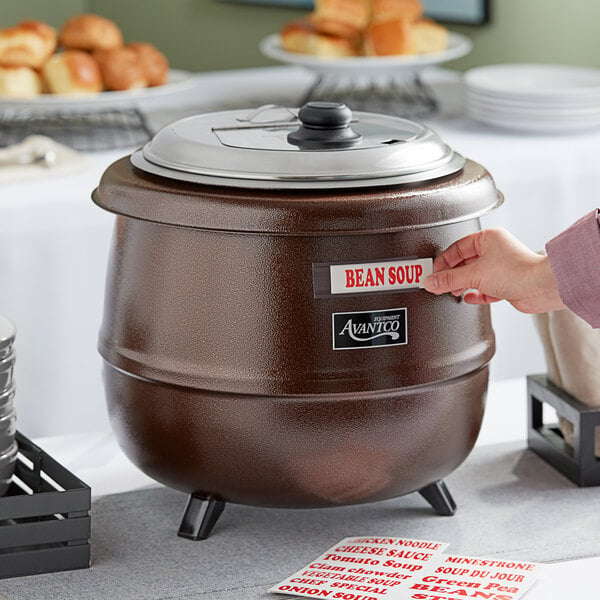 A person using an Avantco copper soup kettle to open bean soup.