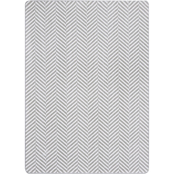 A Joy Carpets Morning Fog area rug with a grey and white chevron pattern and white border.