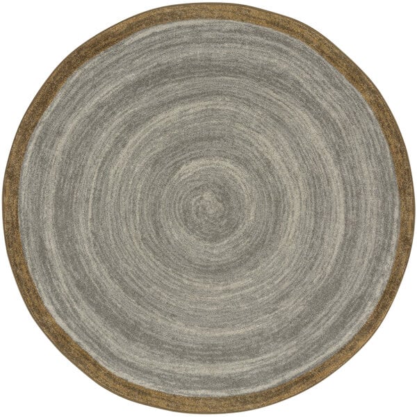 A round stone area rug with a brown border and gray and brown designs.