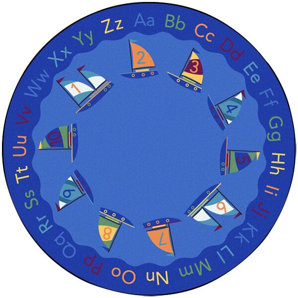 A round multicolored area rug with sailboats, flags, and letters in blue, white, and orange.