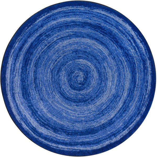 A blue circular rug with a spiral pattern.