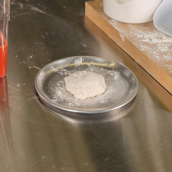 A dough ball on an American Metalcraft aluminum coupe pizza pan.