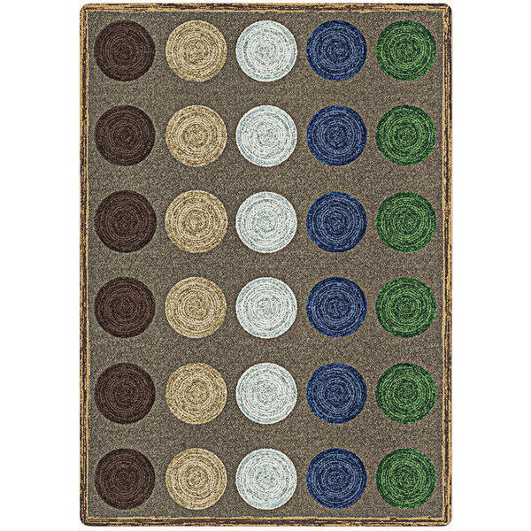 A close-up of a multicolored Joy Carpets rectangular area rug with circles and dots in brown, green, and blue.