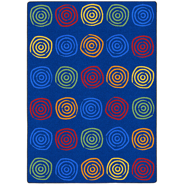 A blue Joy Carpets area rug with colorful circles.