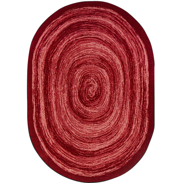 A red oval rug with a white spiral design.