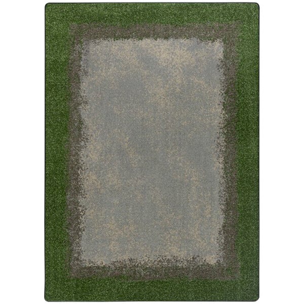A Joy Carpets rectangular area rug with a white background and a green and gray border with a grass field inside.