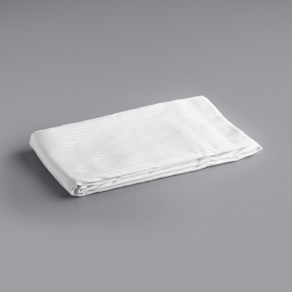 An Oxford white and gray striped bed topper on a gray surface.