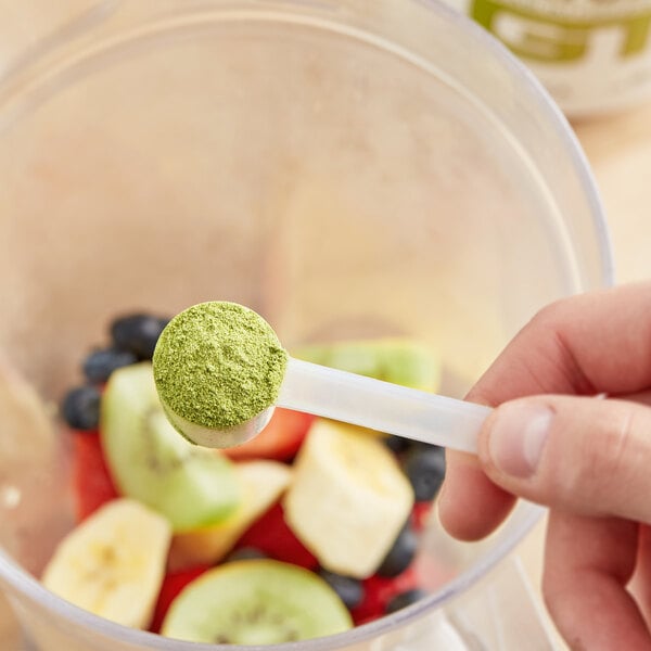 A hand holding a spoon with Add A Scoop Premium Matcha Green Tea powder in it.