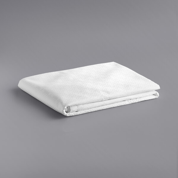 A stack of folded white Oxford Super Blend Queen Size bed toppers on a gray surface.