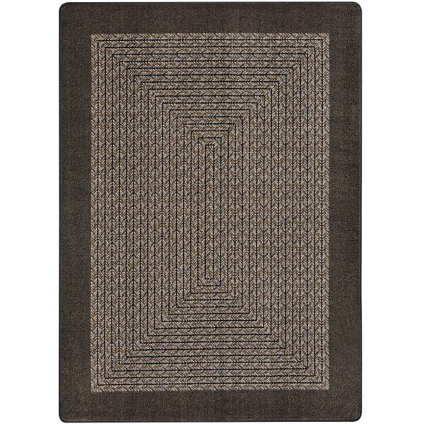 A close-up of a Joy Carpets chocolate brown rectangular area rug with a geometric design.