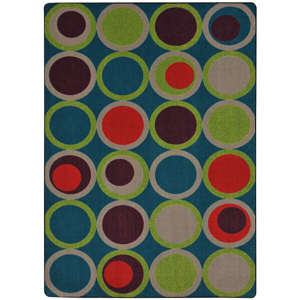 A Joy Carpets rectangle area rug with blue, green, and red circles on a blue background.