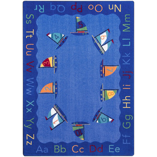 A blue rectangular area rug with green and red sailboats and letters on it.