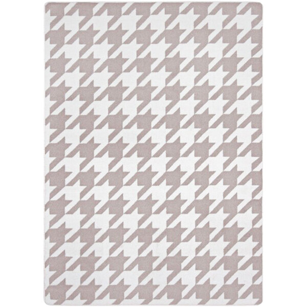 A taupe area rug with a houndstooth pattern in white.