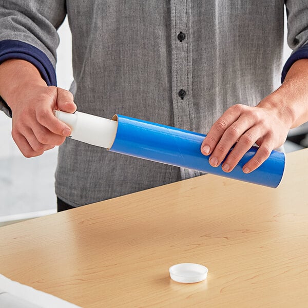 A person holding a Lavex blue mailing tube with a blue cap.