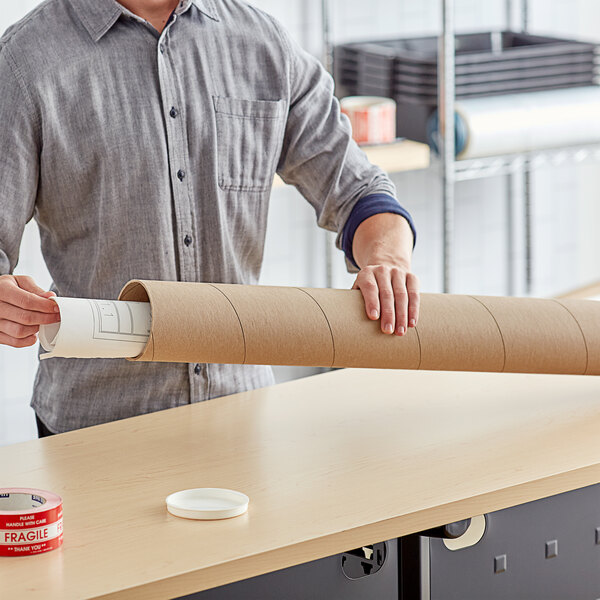 A person holding a Lavex Kraft Mailing Tube roll of brown paper.