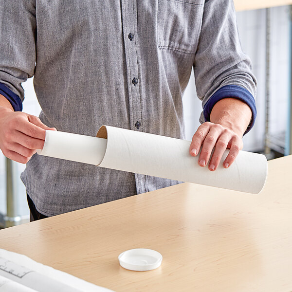 A person holding a Lavex white mailing tube filled with paper.