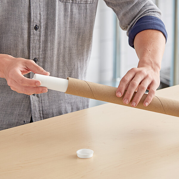 A person holding a long brown Lavex kraft mailing tube.