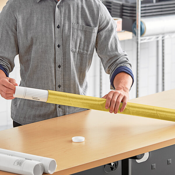 A man holding a roll of white paper in a Lavex gold mailing tube.