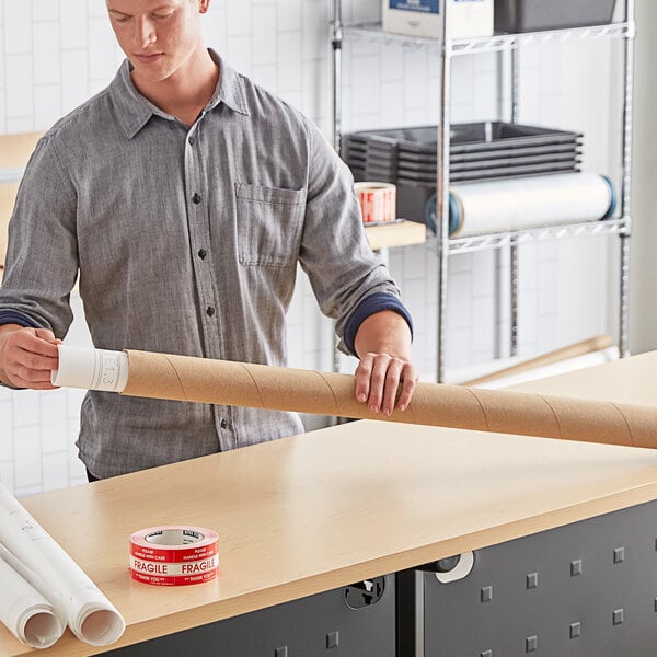 A man holding a long roll of Lavex Kraft cardboard mailing tubes.