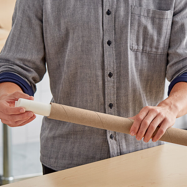 A person holding a Lavex Kraft mailing tube on a table.