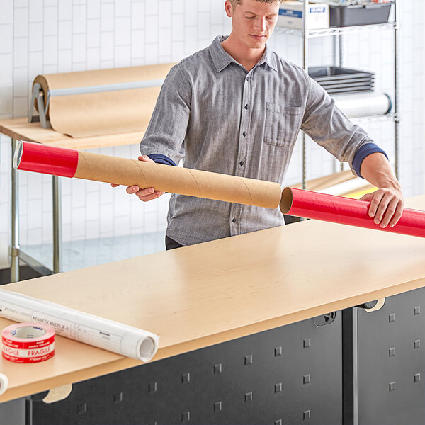 A man holding a red telescoping mailing tube.